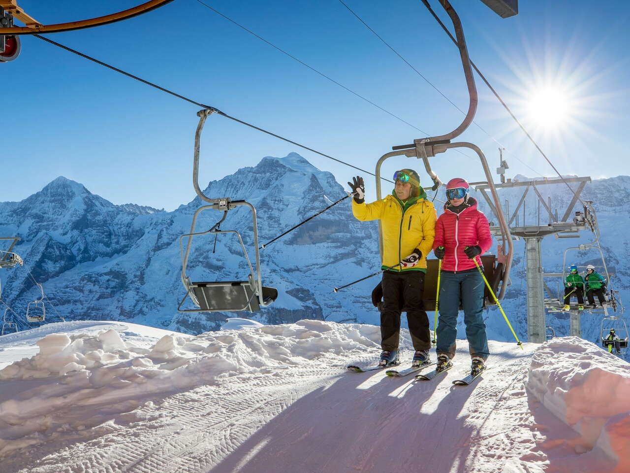 Skiers stand up from the chairlift in the Mürren-Schilthorn ski area. The Eiger, Mönch and Jungfrau triumvirate can be seen from afar.