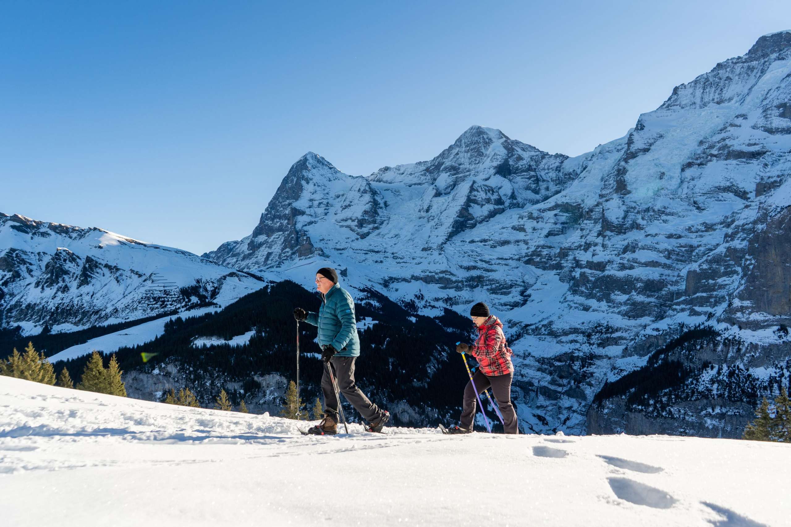 Unterwegs in der verschneiten Landschaft bei sonnigem Wetter mit den Schneeschuhen. Der Schneeschuhtrail in Mürren bietet eine einmalige Sicht auf Eiger, Mönch und Jungfrau.